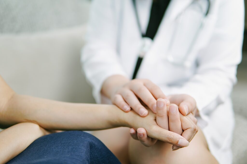 Doctor holding hands to comfort patient